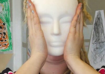 Plaster Cast white face held infront of a womens own face.