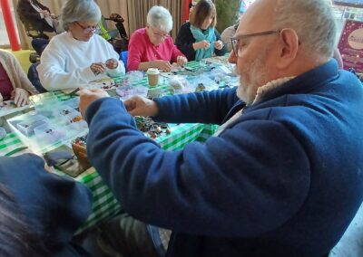 Group creating jewelry at a workshop with beads and tools on a green checked tablecloth