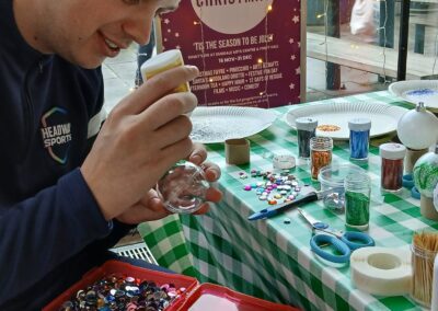 Man crafting Christmas ornament at a seasonal workshop with glitter and sequins.