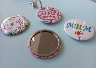 Handmade "Mum" pocket mirrors with colorful designs on a blue surface.