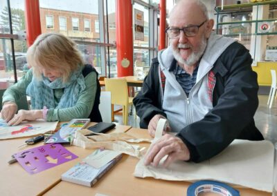 Seniors crafting with fabric markers and stencils at a table.