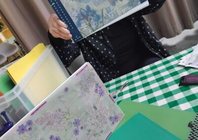 Woman crafting scrapbook with floral designs and green checkered table.