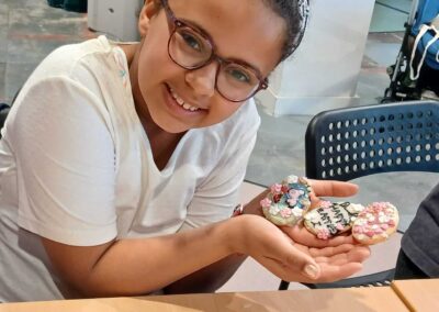 Girl smiling, holding decorated Easter cookies. One cookie reads "Happy Easter.