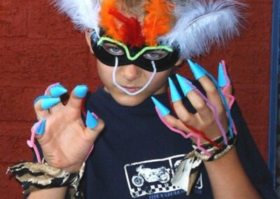 Boy in homemade costume mask and claw gloves, posing.