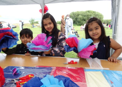 Kids crafting colorful tissue paper flowers at an outdoor event.