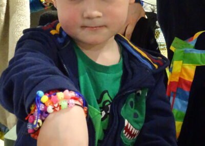 Young boy wearing a colorful beaded bracelet and a green dinosaur shirt.