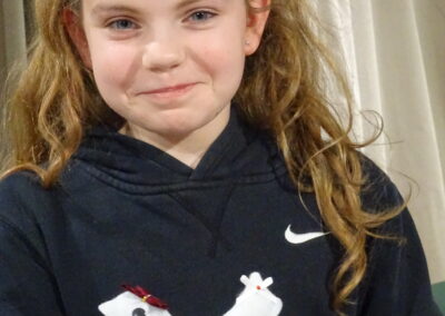 Girl in Nike hoodie holds a handmade felt bird ornament with floral accents.