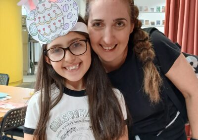 Girl with bunny ears headband smiles with woman. Easter crafting fun.