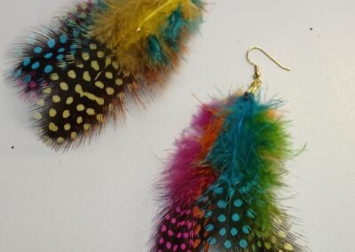 Colorful feather earrings with gold hooks, one yellow and one with pink and teal.