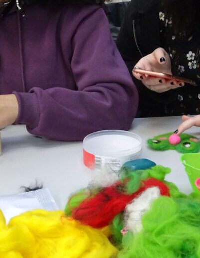 Needle felting craft: People making felted frogs with wool and tools.
