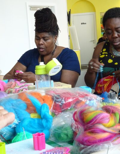 Women felting colorful wool fibers at a crafting workshop.