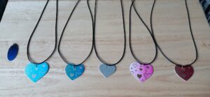 Colorful heart necklaces on a wooden surface, handmade jewelry
