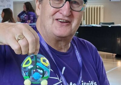 Woman in Meningitis Research Foundation shirt holding handmade ornament.