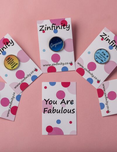 Zinfinity pins with positive messages: "Gorgeous," "Fabulous," "Proud To Be Me," and "Don't Compare Me.