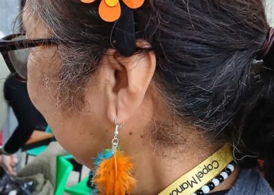 Woman wearing a flower headband and feather earrings. Capel Manor College lanyard visible.