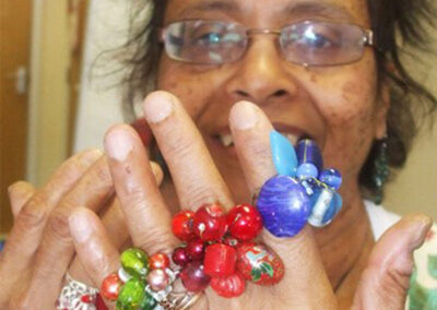 Woman with multiple colorful beaded rings on her fingers, smiling at the camera.